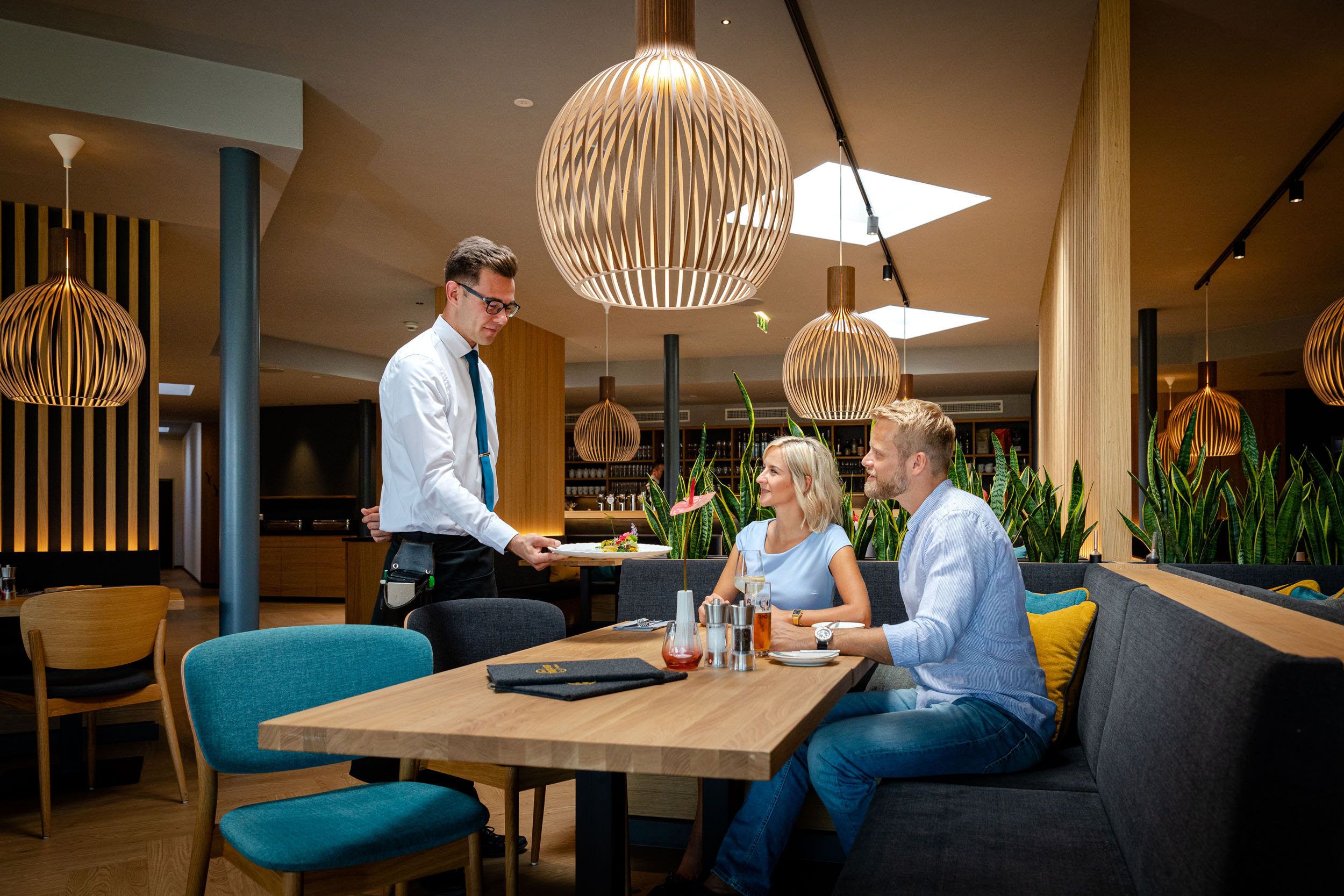 Ein Kellner serviert einem Paar das Essen im Gasthaus in Villach Umgebung